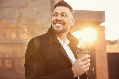 Photo of Man with cup of coffee on city street in morning