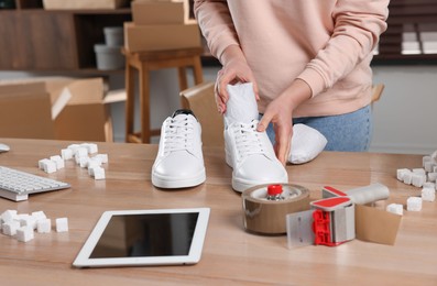 Seller packing shoes at workplace, closeup. Online store