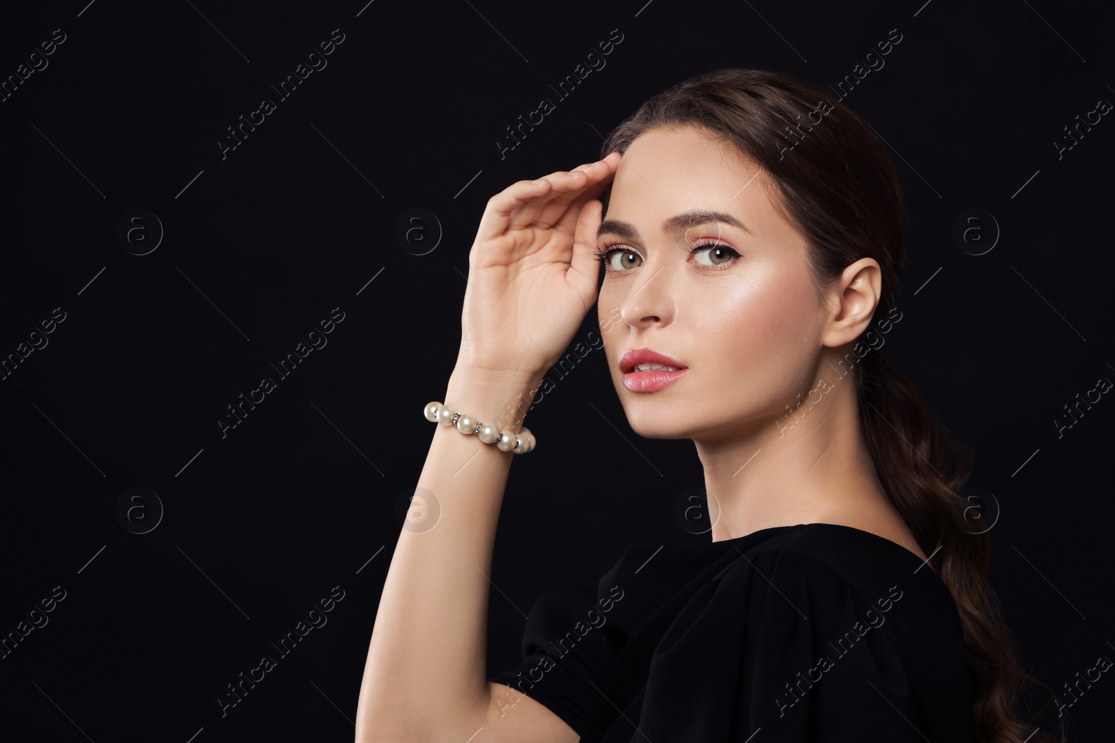 Photo of Young woman wearing elegant pearl bracelet on black background, space for text