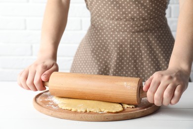 Photo of Making shortcrust pastry. Woman rolling raw dough at white wooden table, closeup