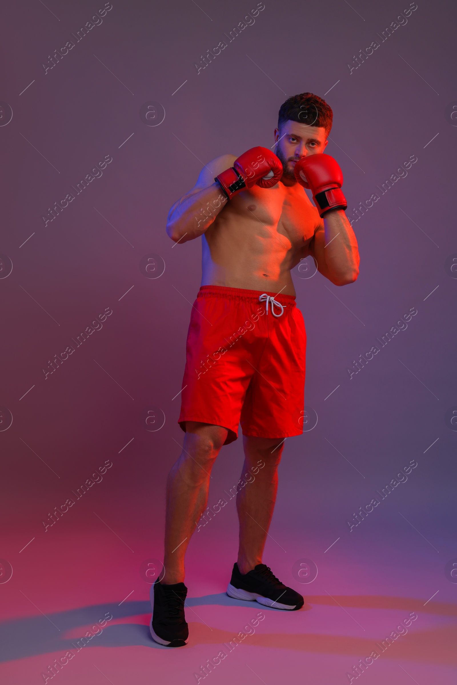 Photo of Man in boxing gloves on color background