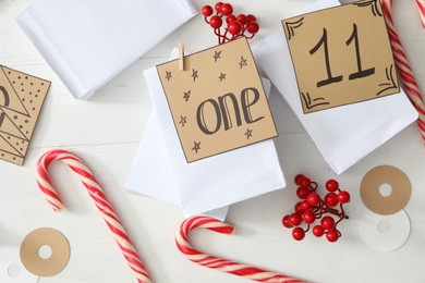 Photo of Flat lay composition with gift bags on white wooden table. Creating advent calendar
