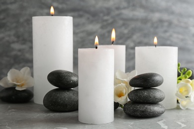 Photo of Burning candles, spa stones and flowers on table