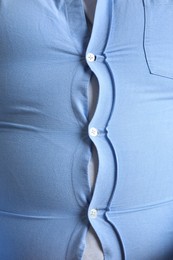 Closeup view of overweight man in tight shirt as background