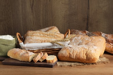 Fresh crispy ciabattas and baguettes on wooden table