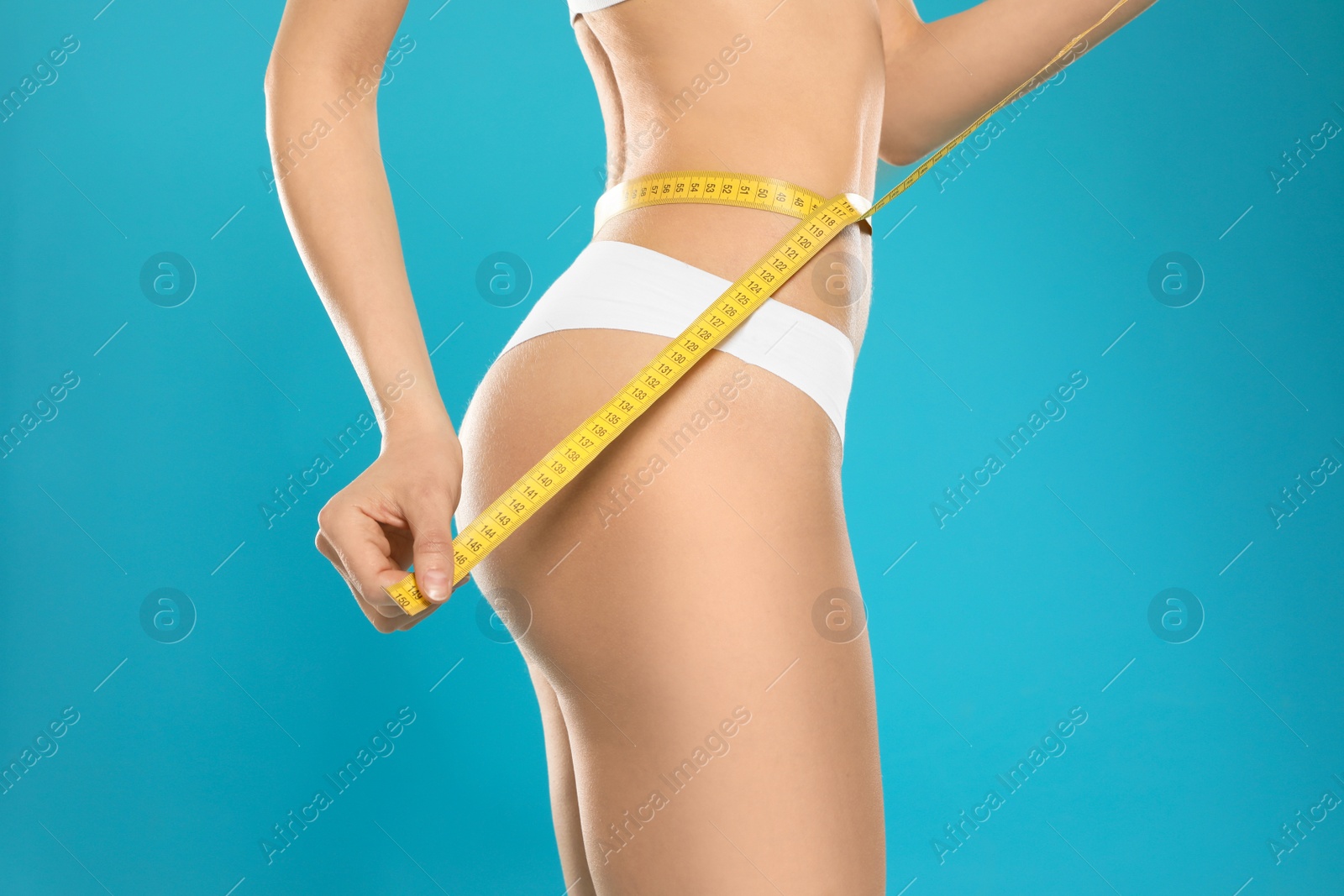 Photo of Slim young woman with smooth gentle skin in underwear measuring body on color background, closeup