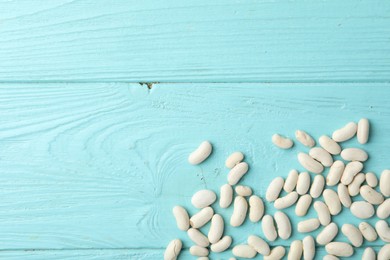 Raw beans and space for text on light blue wooden background, flat lay. Vegetable seeds