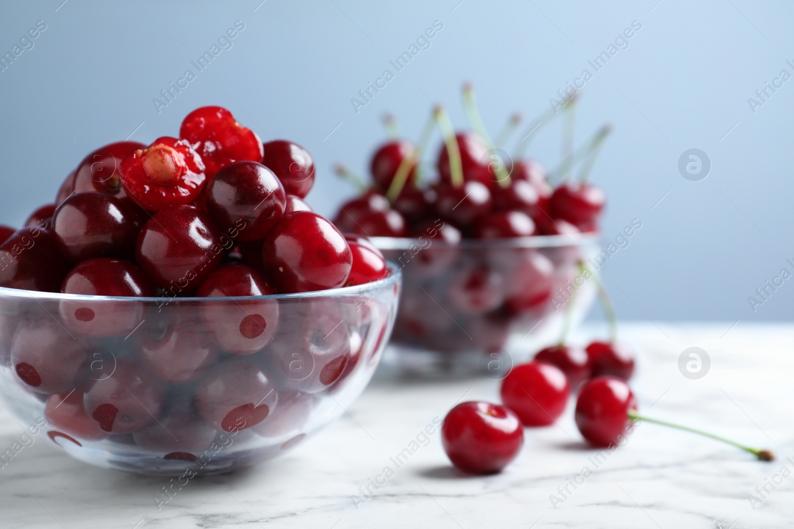 Photo of Sweet juicy cherries on white marble table, closeup