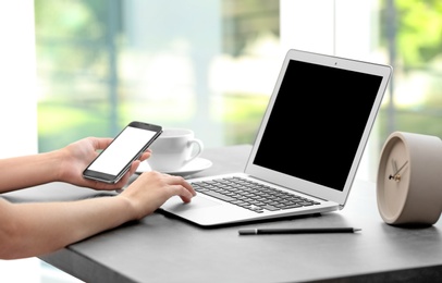 Photo of Woman working with laptop and smartphone at table. Mock up with space for text