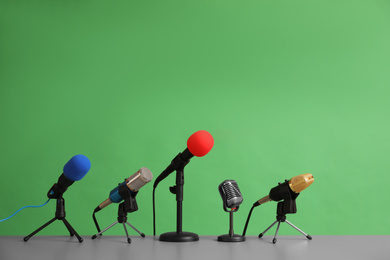 Photo of Microphones on table against green background. Journalist's work