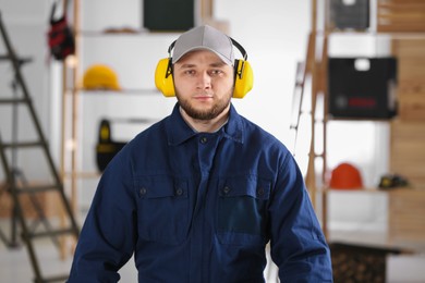 Worker wearing safety headphones indoors. Hearing protection device