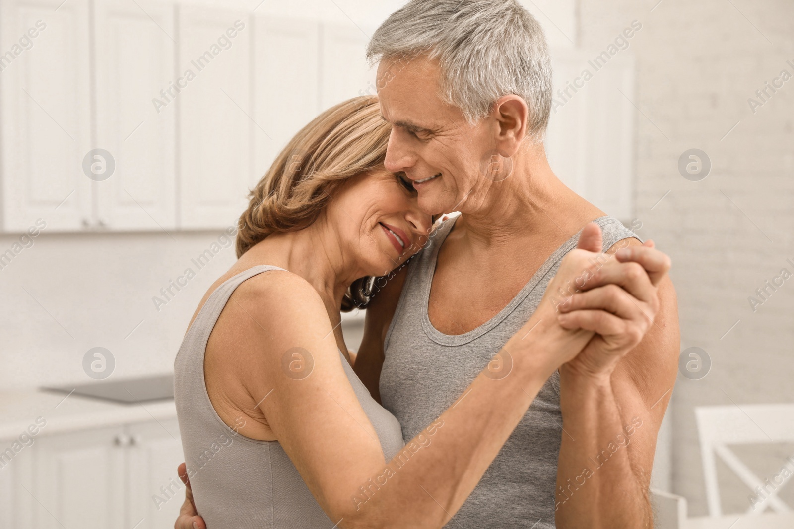 Photo of Happy senior couple dancing together in kitchen