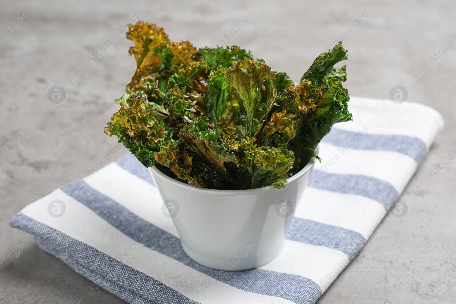 Photo of Tasty baked kale chips on grey table