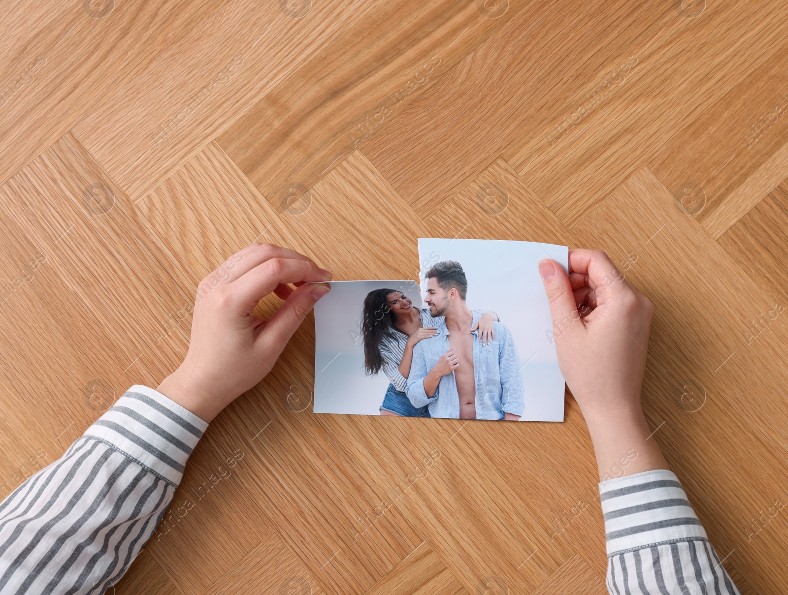 Photo of Woman ripping photo at wooden table, top view. Divorce concept