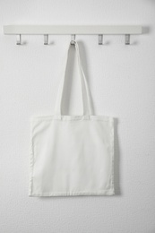 Photo of Tote bag hanging on white wall. Mock up for design