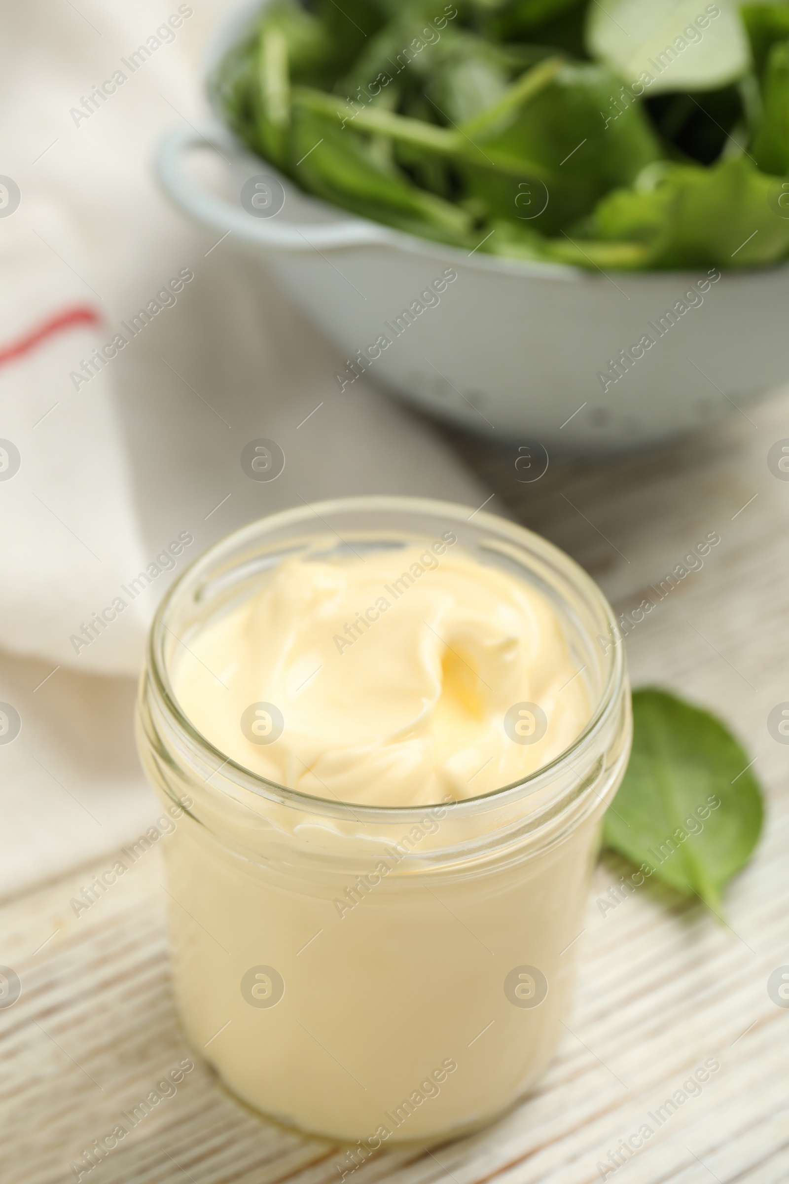 Photo of Jar of delicious mayonnaise and fresh spinach on white wooden table