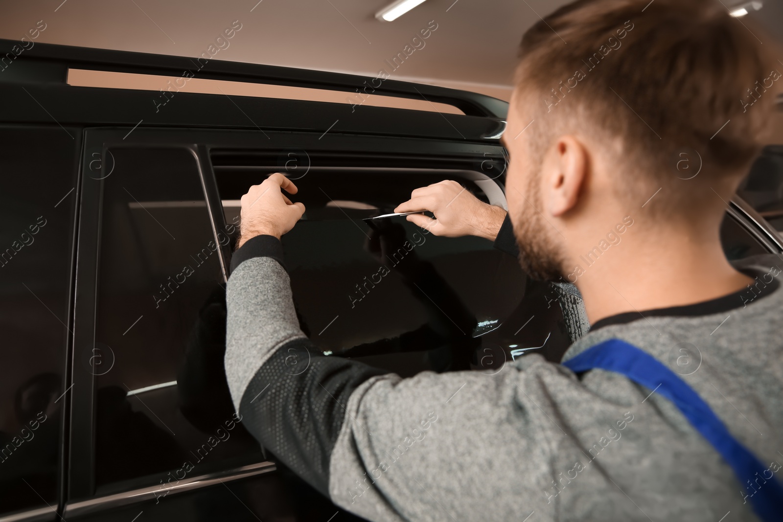 Photo of Skilled worker tinting car window in shop