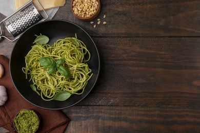 Photo of Delicious pasta with pesto sauce and basil on wooden table, flat lay. Space for text