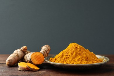 Photo of Plate with aromatic turmeric powder and cut roots on wooden table. Space for text