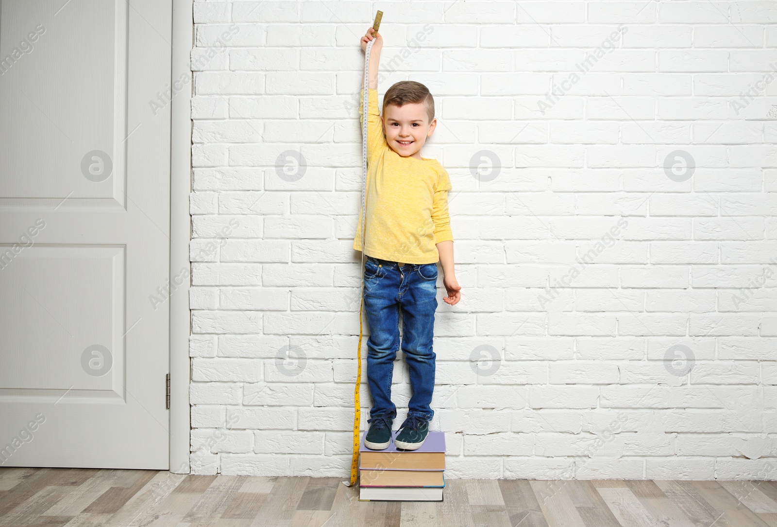 Photo of Little boy measuring his height near brick wall