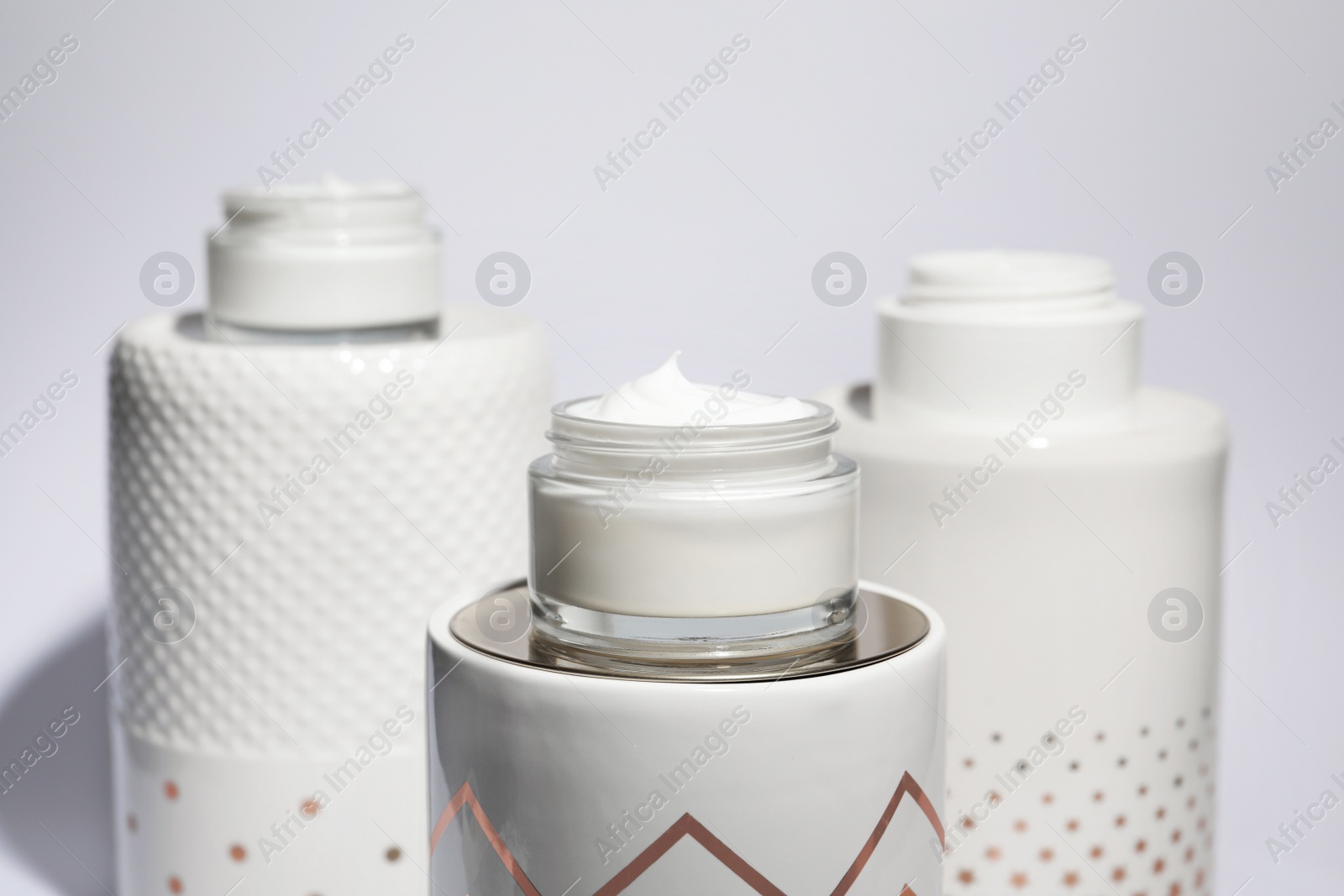 Photo of Open jars of cream on display against light background
