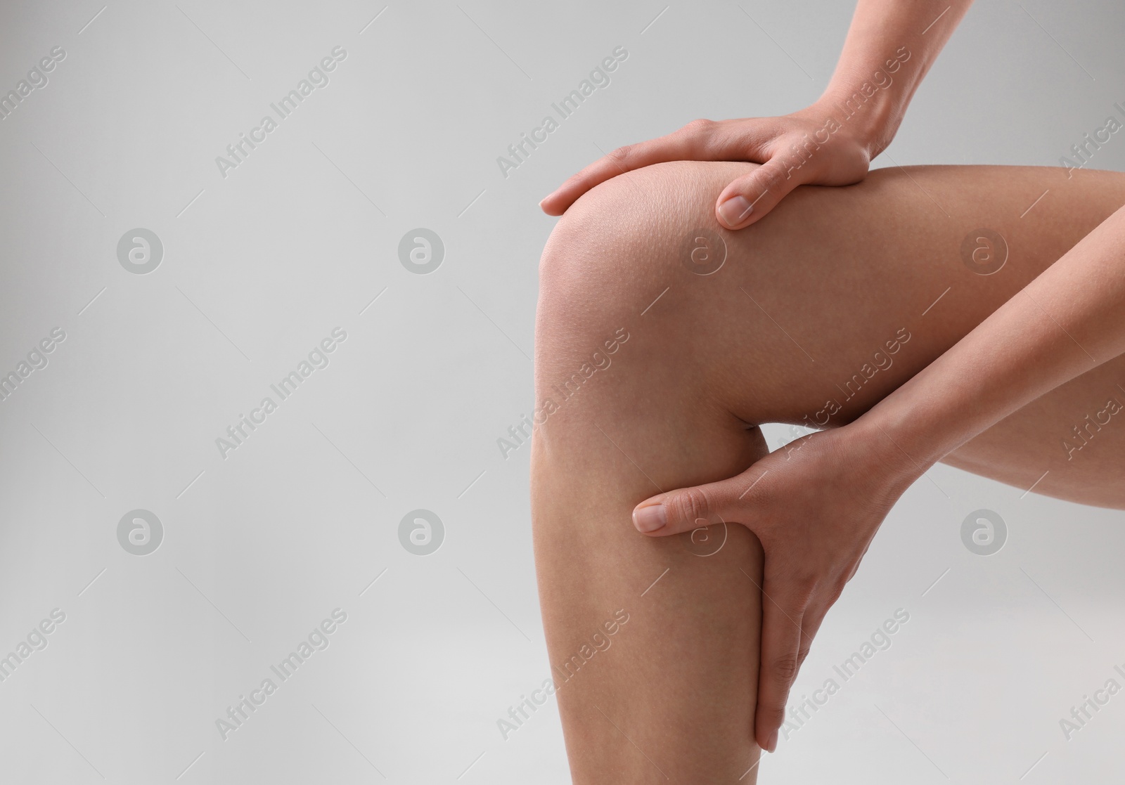 Photo of Woman showing her slim legs on grey background, closeup. Space for text