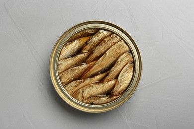 Photo of Open tin can of sprats on light grey table, top view