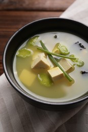 Photo of Bowl of delicious miso soup with tofu on wooden table, closeup