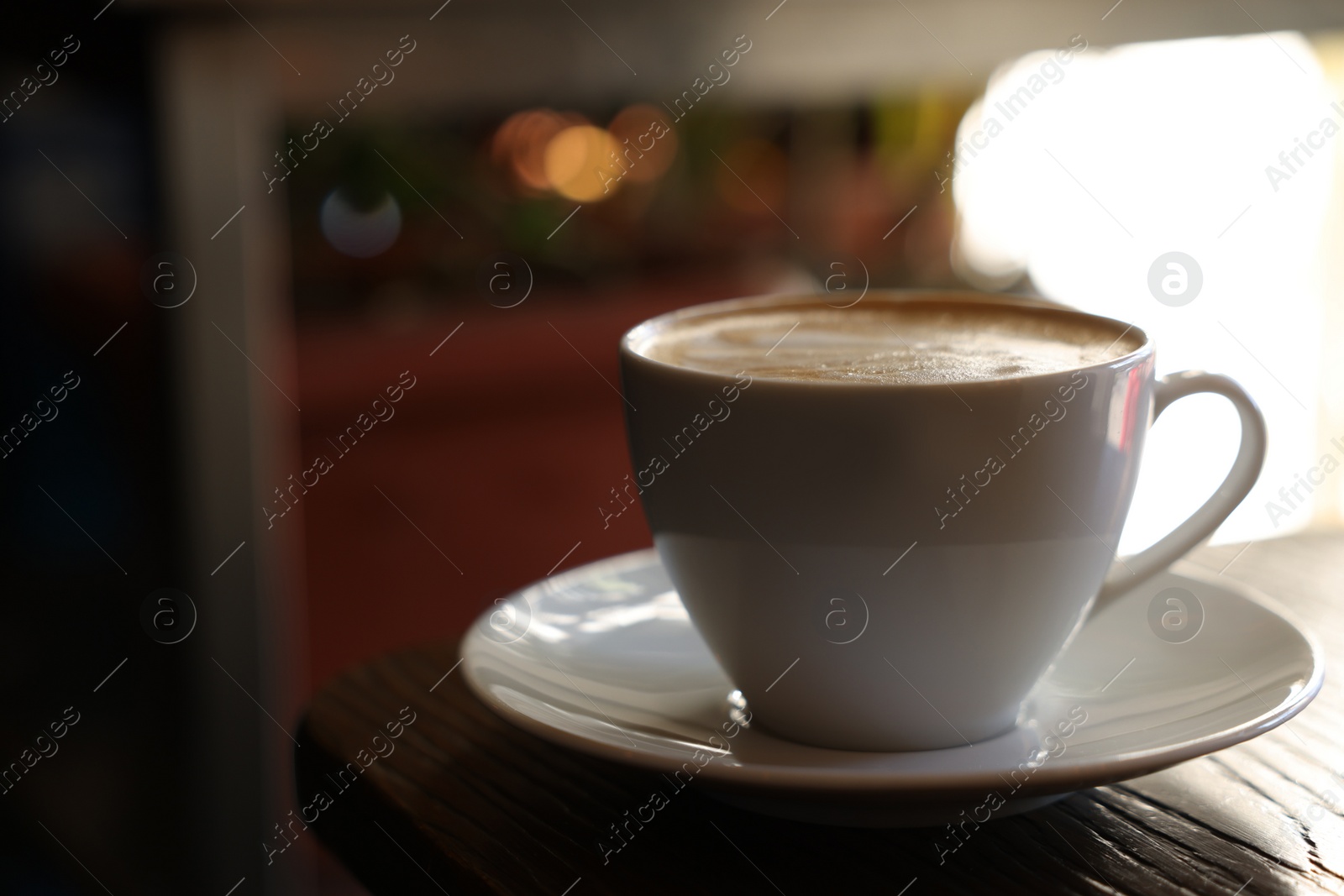 Photo of Cup of aromatic coffee with foam on table in cafe. Space for text