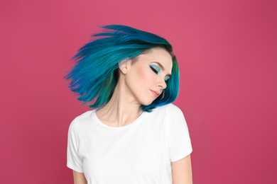 Young woman with bright dyed hair on pink background