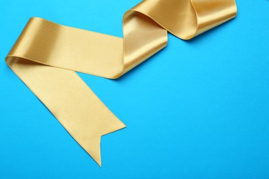 Photo of Beautiful golden ribbon on light blue background. Space for text