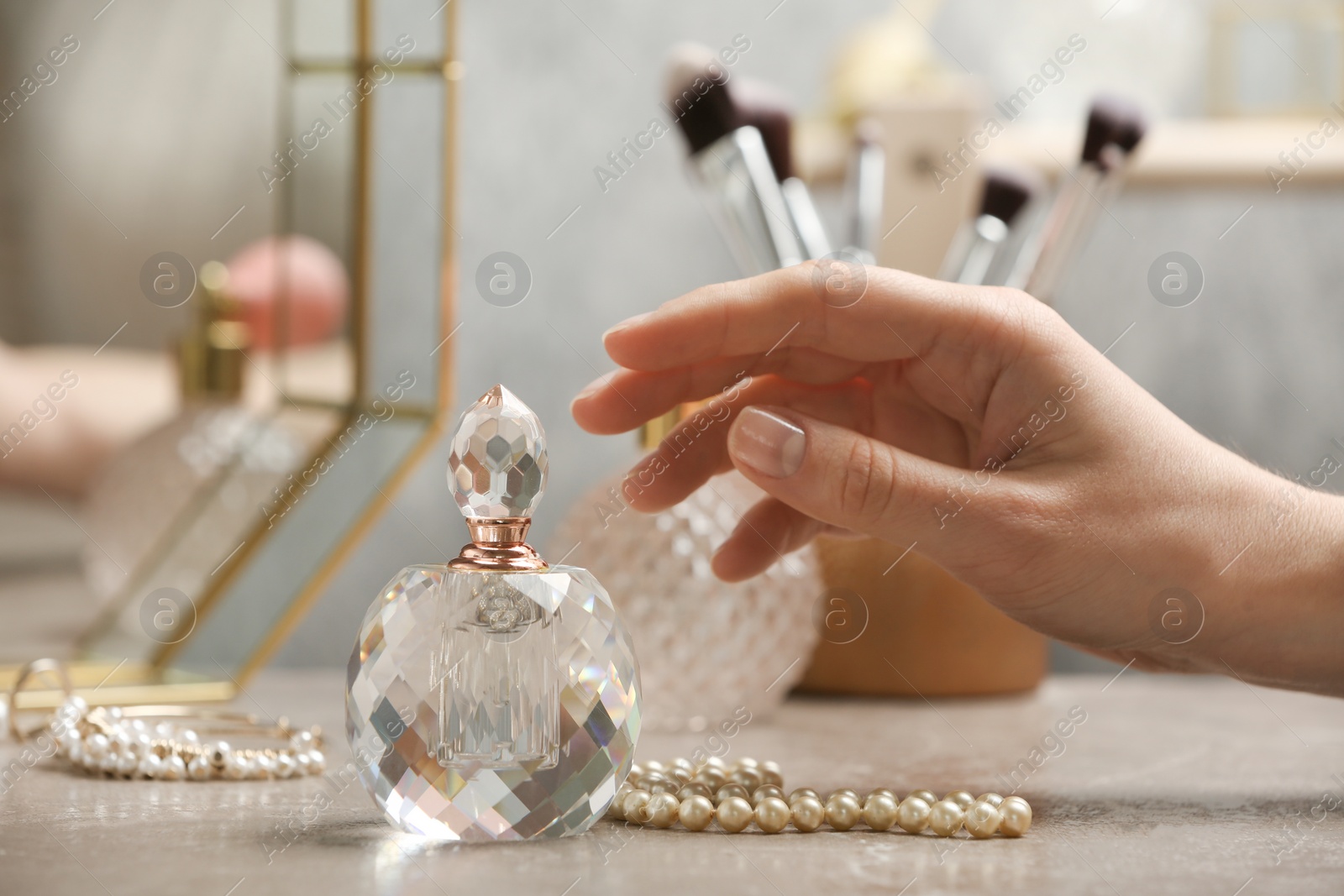 Photo of Woman reaching for crystal bottle of luxurious perfume on dressing table, closeup