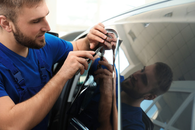 Photo of Worker tinting car window with foil in workshop