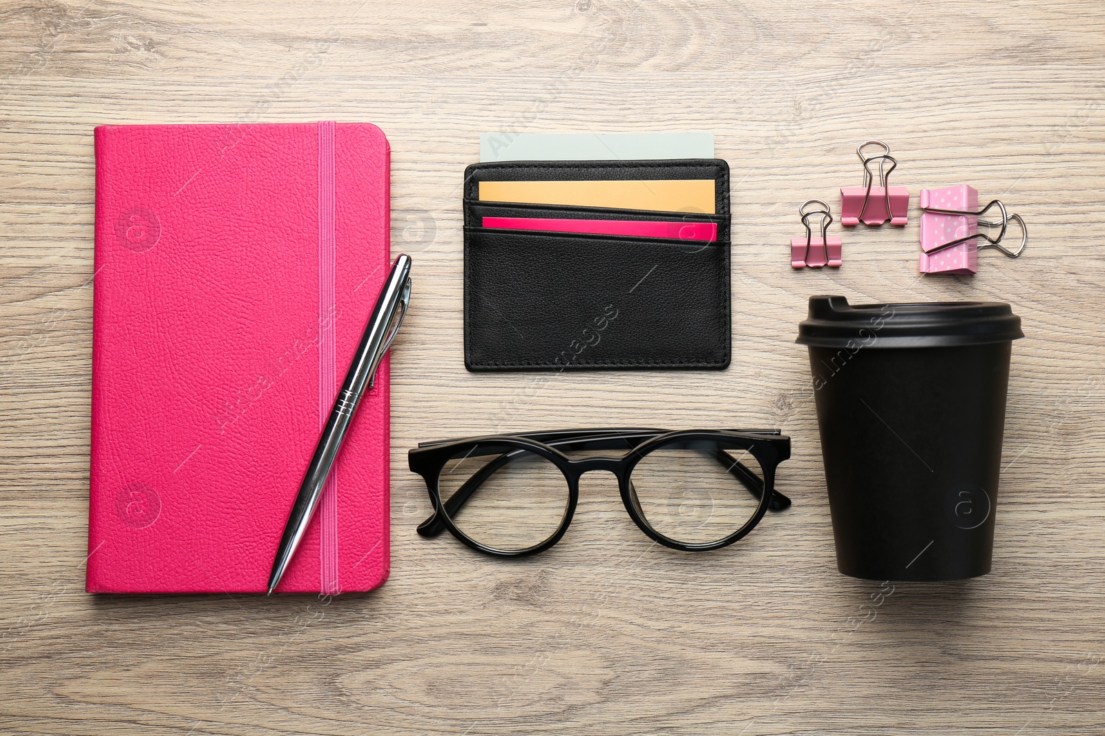 Photo of Leather business card holder with colorful cards, stationery, glasses and coffee on wooden table, flat lay