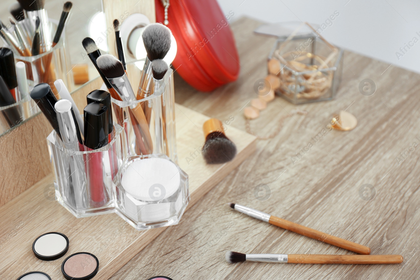 Photo of Organizer with cosmetic products for makeup on table near mirror