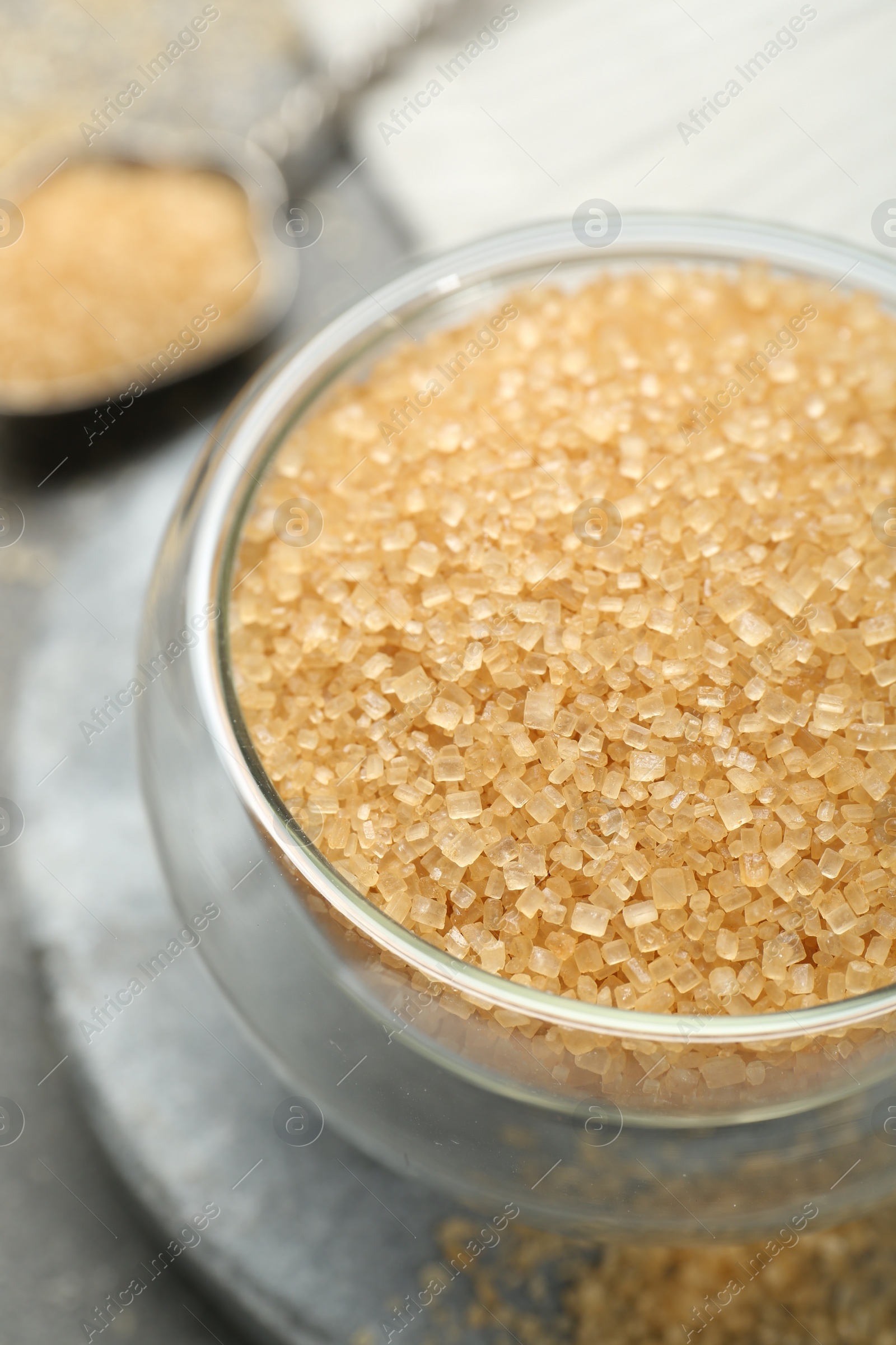 Photo of Brown sugar in bowl on grey table, closeup