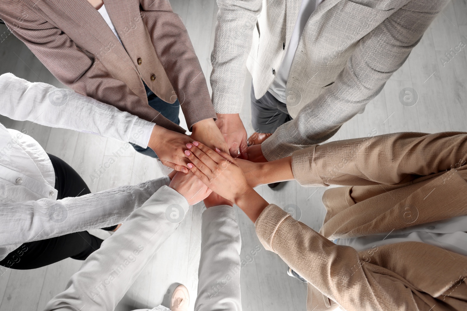 Photo of Group of people holding hands together indoors, above view. Unity concept