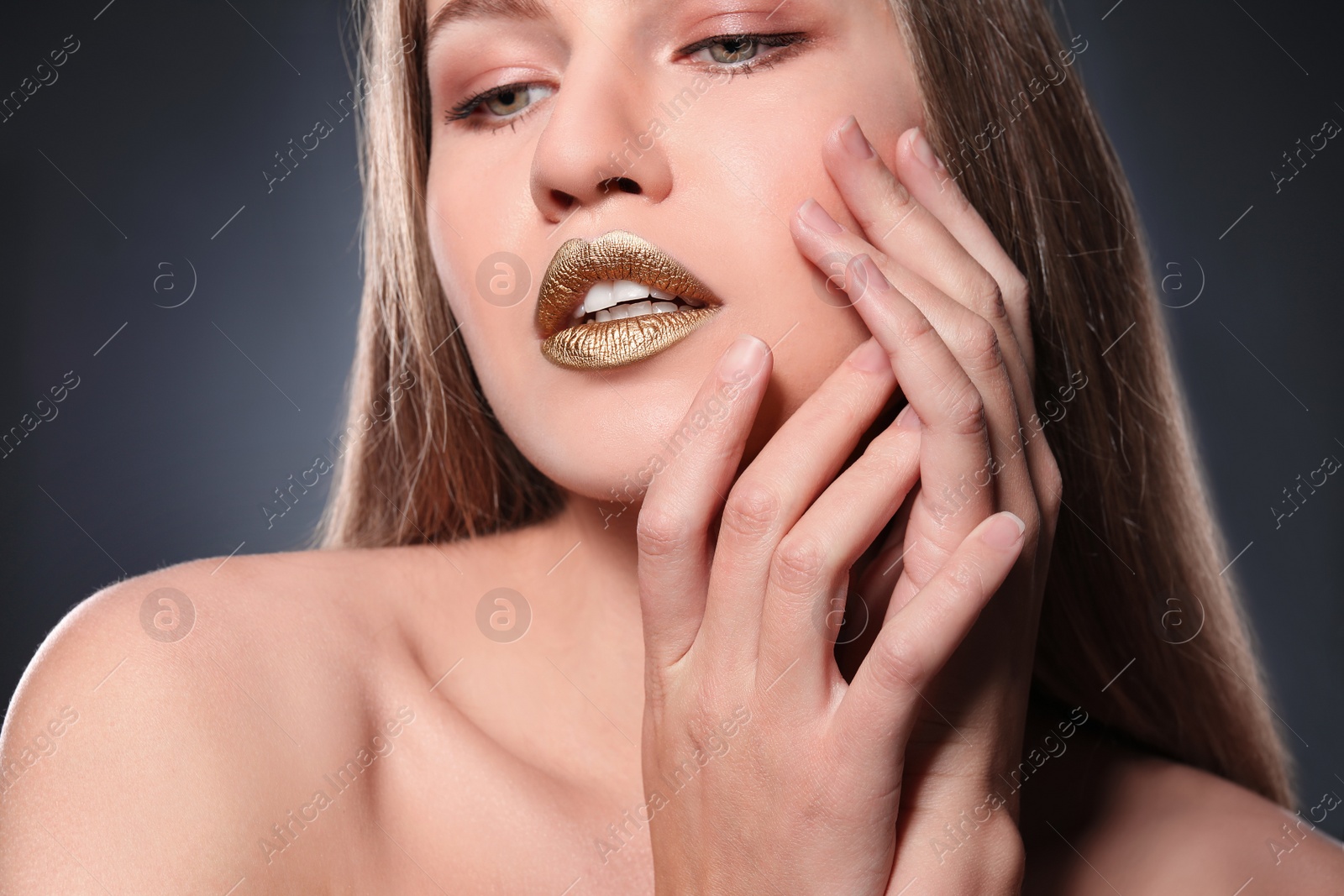 Photo of Woman with gold lipstick on grey background, closeup