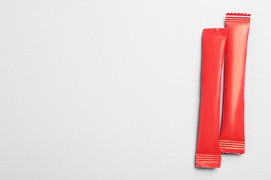 Red sticks of sugar on light grey background, flat lay. Space for text
