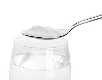 Spoon with baking soda over glass of water on white background