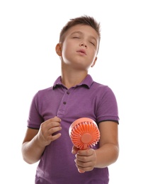 Photo of Little boy with portable fan suffering from heat on white background. Summer season