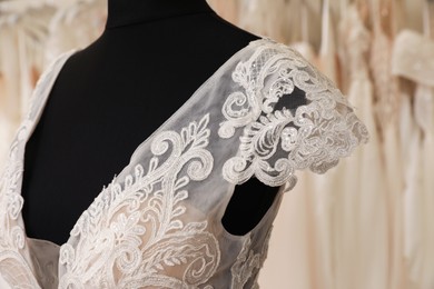 Photo of Beautiful wedding dress on mannequin in boutique, closeup