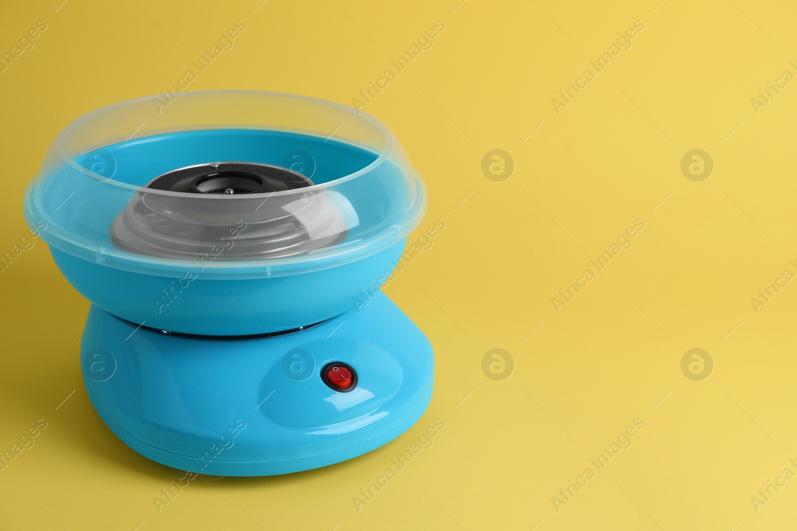 Photo of Portable candy cotton machine on yellow background, space for text