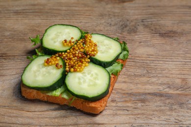 Photo of Tasty cucumber sandwich with arugula and mustard on wooden table