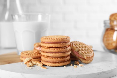 Photo of Tasty sandwich cookies with cream and milk on white board