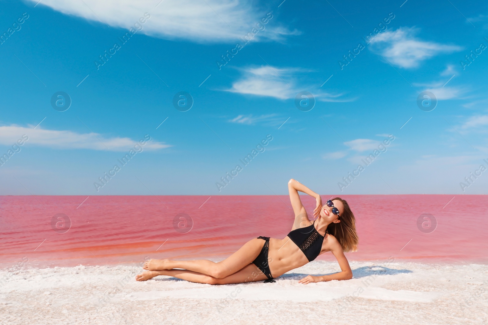 Photo of Beautiful woman in swimsuit lying near pink lake on sunny day