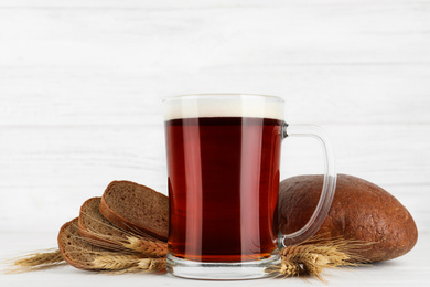 Photo of Composition with delicious kvass, spikes and bread on white table