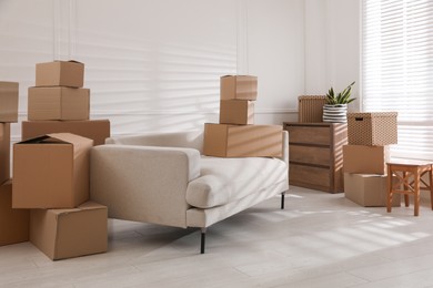 Photo of Furniture and cardboard boxes with packed stuff in room. Moving day