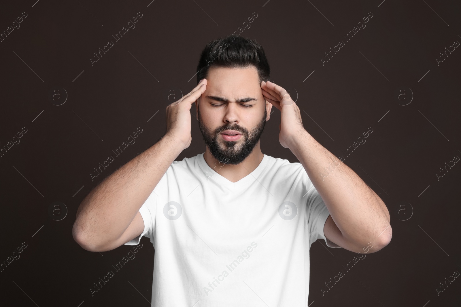 Photo of Young man suffering from headache on dark background