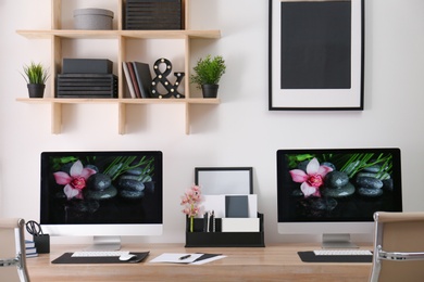 Photo of Modern workplace with large desk and computers in room. Stylish interior